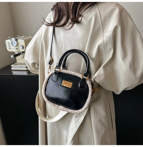 Detail of black glossy pillow bag with faux shearling trim and gold hardware brand plate