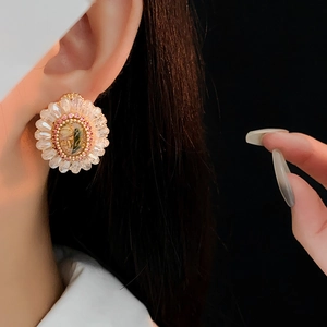 Close-up of vintage flower stud earring with pink crystals and gold finish on ear