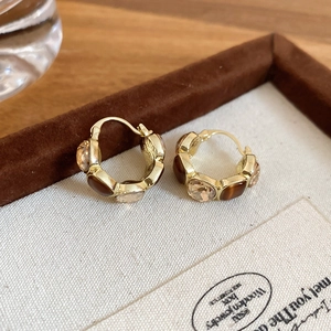 Close-up of golden tiger eye heart earrings with champagne stones in a wooden jewelry box