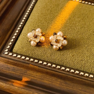 Close-up of vintage flower earrings with pearls and zircon on green fabric