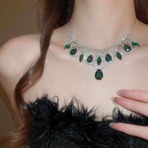 Close-up of luxury silver necklace with emerald teardrop pendant and crystal fringe detail