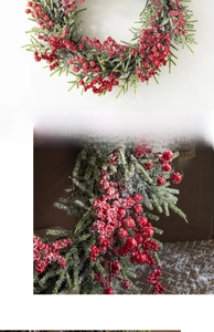 Detail of Christmas wreath featuring red berries, green pine needles and artificial snow