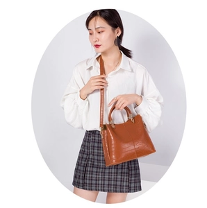 Brown crocodile embossed tote bag with gold hardware worn as shoulder bag by model