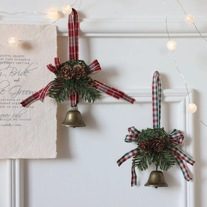 Cloches de Noël avec pommes de pin et ruban écossais rouge sur cheminée décorative