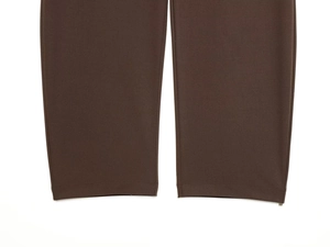 Detail shot of dark brown trousers hemline showing fine stitching and fabric texture
