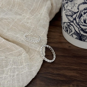 925 Sterling Silver hollow heart woven rings displayed on a rustic wooden table background