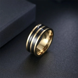 Dettaglio di un anello da uomo largo in titanio nero e oro con design a strisce