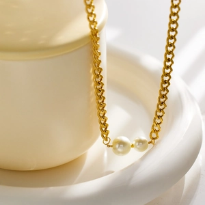 Detailed close-up of a gold-plated stainless steel chain with double pearl pendants