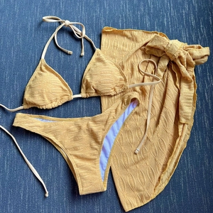 Detail of ginger yellow bikini set showing textured leaf-pattern fabric and matching sarong