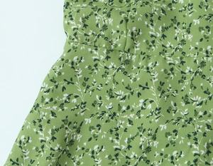Détail du tissu à fleurs et couture à la taille sur une robe d'été verte à bretelles