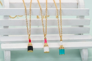 Detailed view of three lipstick pendants with enamel coating and shimmering rhinestones