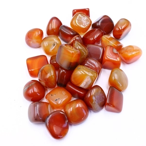 Polished natural carnelian stones with rich orange-red hues on white background