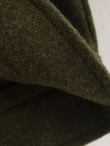 Primer plano de la textura de lana verde oliva oscuro con costuras detalladas para chaqueta