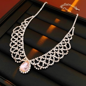 Detail of silver necklace with pink teardrop crystal and intricate rhinestone lace patterns
