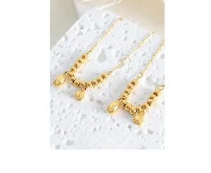 Detailed close-up of 18k gold-plated lotus pod and lily bud charm ankle chain jewelry