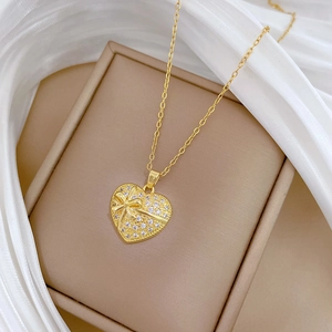 Collier élégant avec pendentif cœur doré, cristaux brillants et nœud sur soie