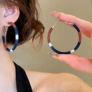 Detail of colorful woven thread on large circular earrings with vintage ethnic style textures