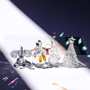 Detailed view of clear crystal Christmas ornaments featuring snowman and tree on a desk