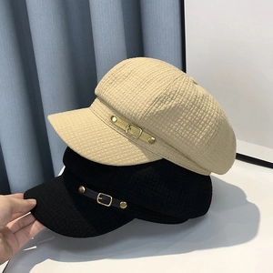 Detailed view of fashionable newsboy hat featuring textured waffle fabric and metal buckle