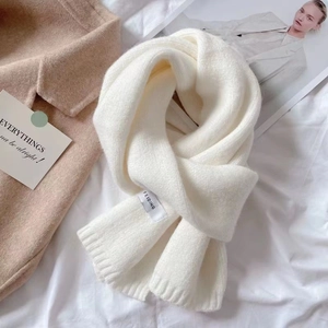 Flat lay of cream knitted scarf with Feiding brand tag and stylish lifestyle accessories