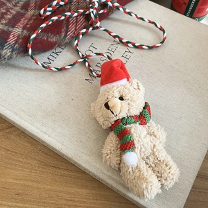 Close-up of beige plush teddy bear pendant with red Santa hat and striped holiday scarf