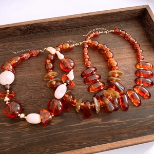 Detailed macro view of irregular amber acrylic beads and gold lobster clasp on necklace