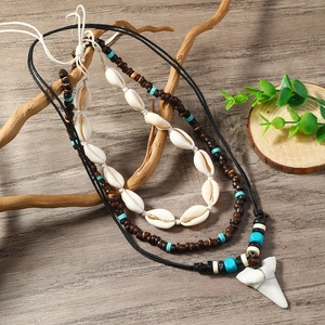 Detail of bohemian layered necklace with white shells, wood beads and shark tooth pendant