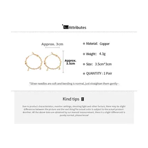Detail view of gold hoop earrings with small spikes and hanging star charms made of copper