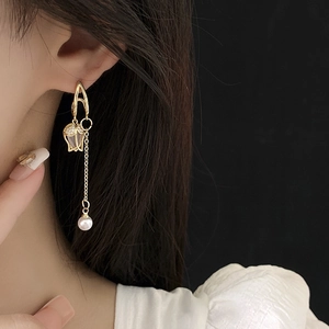 Détail de boucles d'oreilles tulipes avec pampille et perle sur chaîne dorée
