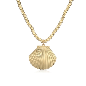 Detailed view of a gold-finish seashell pendant on a vintage-style beaded necklace chain