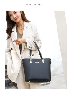 Detail of black faux leather tote bag with gold hardware and metallic brand logo