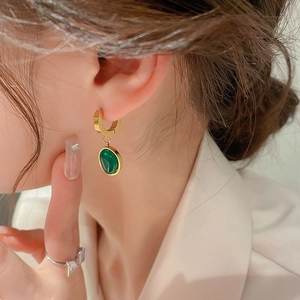 Gros plan de boucles d'oreilles pendantes ovales en résine émeraude et acier doré