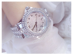 Vue rapprochée d'une montre argentée sertie de cristaux avec chiffres arabes au poignet