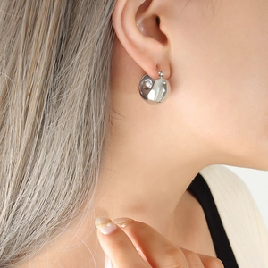 Close-up of minimalist silver water drop earrings worn by a model for size and fit