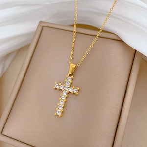 Detailed close-up of a gold cross pendant necklace with zircon inlay in a jewelry box