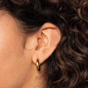 Close-up of classic gold-plated stainless steel hoop earrings worn by a model