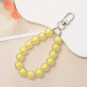 Close-up of candy-colored yellow bead-in-bead charm with silver clasp on white base