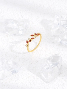 Macro shot of gold leaf-shaped ring with red marquise gems and white pavé stones