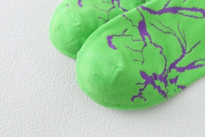 Gros plan de chaussettes en coton vert fluo avec motif éclair violet et finitions nettes