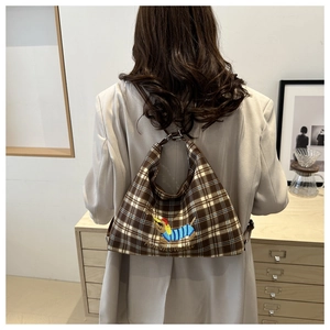 Close-up of brown plaid tote bag featuring a cute dachshund embroidery and metal rings
