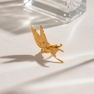 Macro shot of golden swallow ring detailing wing feathers and polished metal finish