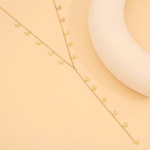 Détail d'une longue chaîne de corps dorée ornée de breloques papillons minimalistes élégantes