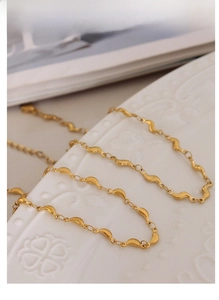 Vue macro d'un collier doré à plaques ondulées sur une assiette en céramique blanche