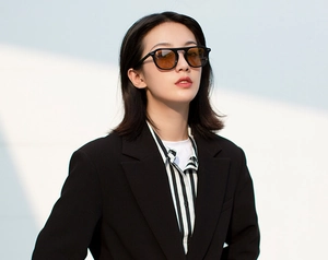 Outdoor shot of stylish round black frame sunglasses with brown lenses on female model
