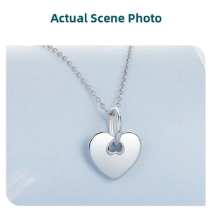Close-up of heart-shaped silver pendant with polished surface on a fine link chain