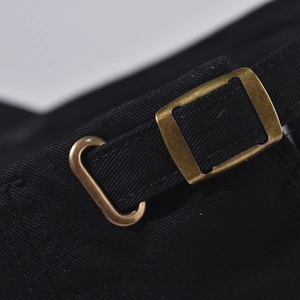Detailed macro view of the black cotton twill fabric and vintage bronze metal buckle