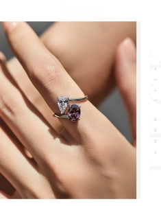 Detail of bypass ring with pear-cut white diamond and oval purple gemstone on hand