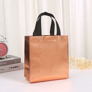 Borsa tote in tessuto non tessuto bronzo metallizzato con manici neri su scrivania