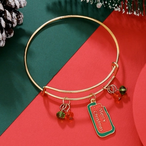 Close-up of golden adjustable Christmas bracelet with red and green charms and festive tag