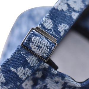 Detail of adjustable metal buckle on blue floral denim baseball cap with premium texture